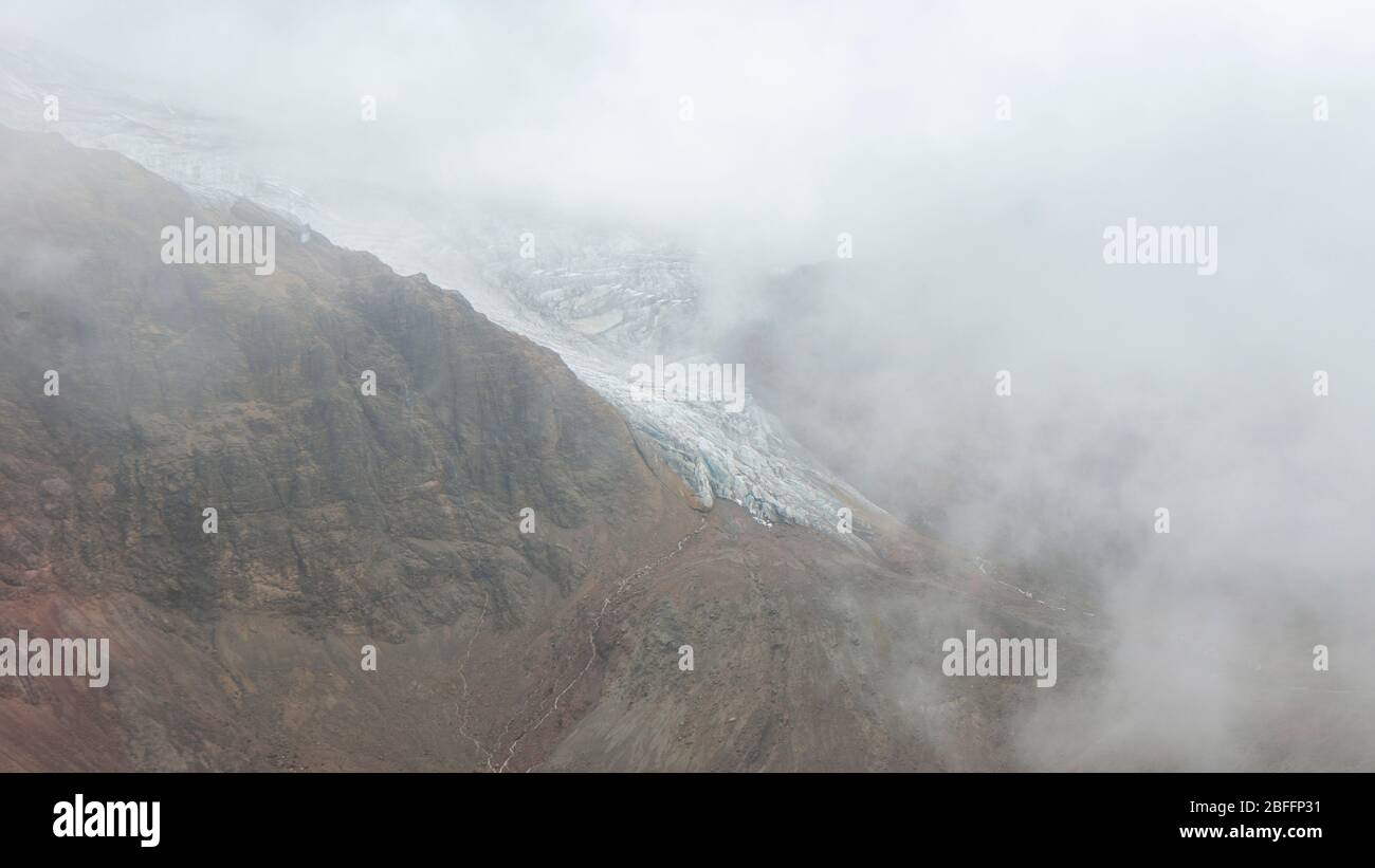 Vista sul ghiacciaio del vulcano Cayambe che scende lungo il pendio in una giornata nuvolosa - Ecuador Foto Stock