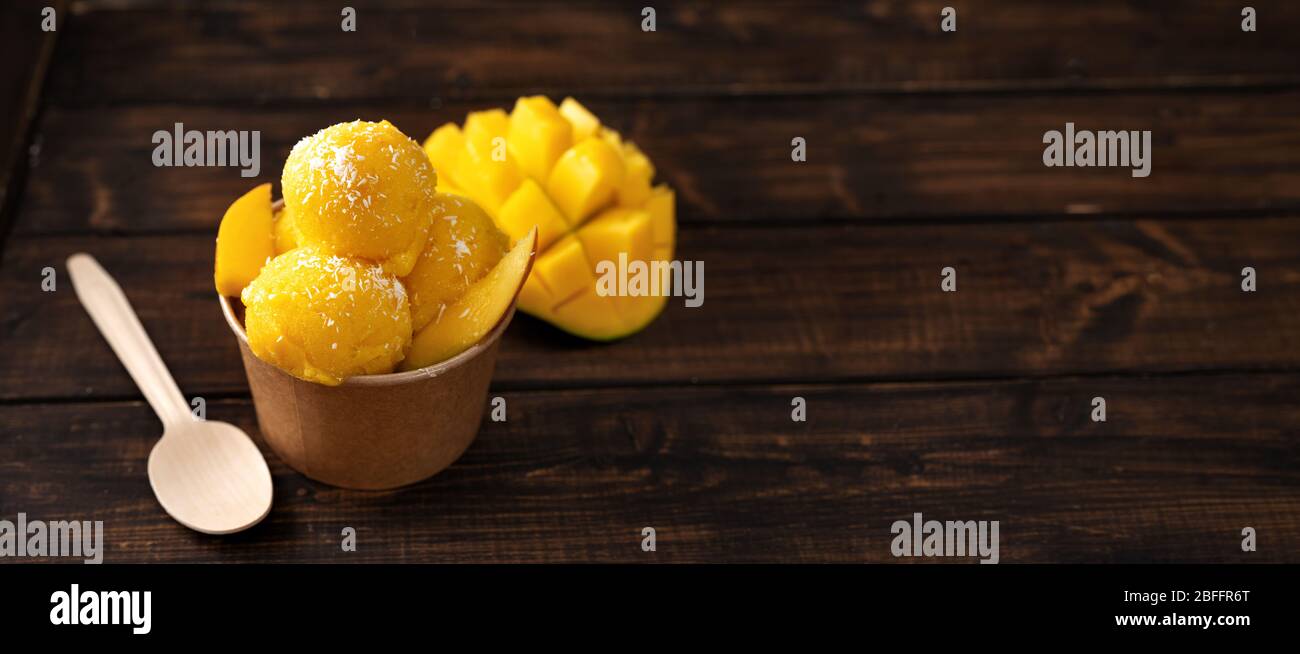 Gelato al mango yummy in tazza di carta artigianale al buio sfondo rustico Foto Stock