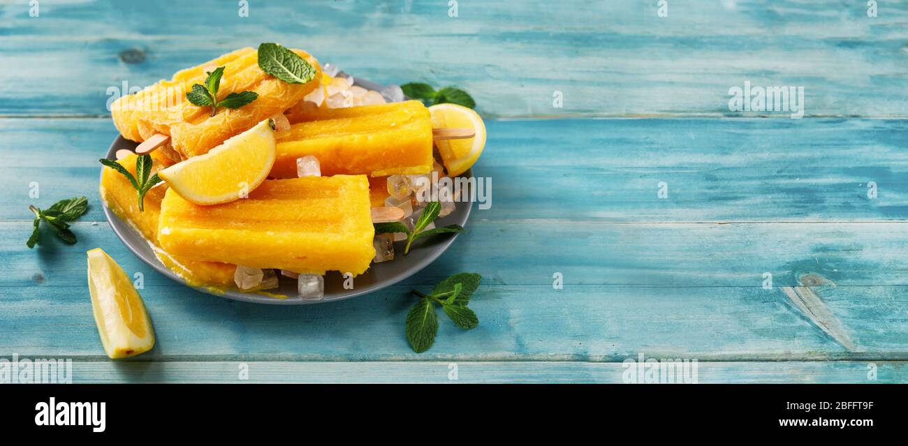 Il sorbetto al mango vegano popsicles su sfondo turchese alla moda Foto Stock