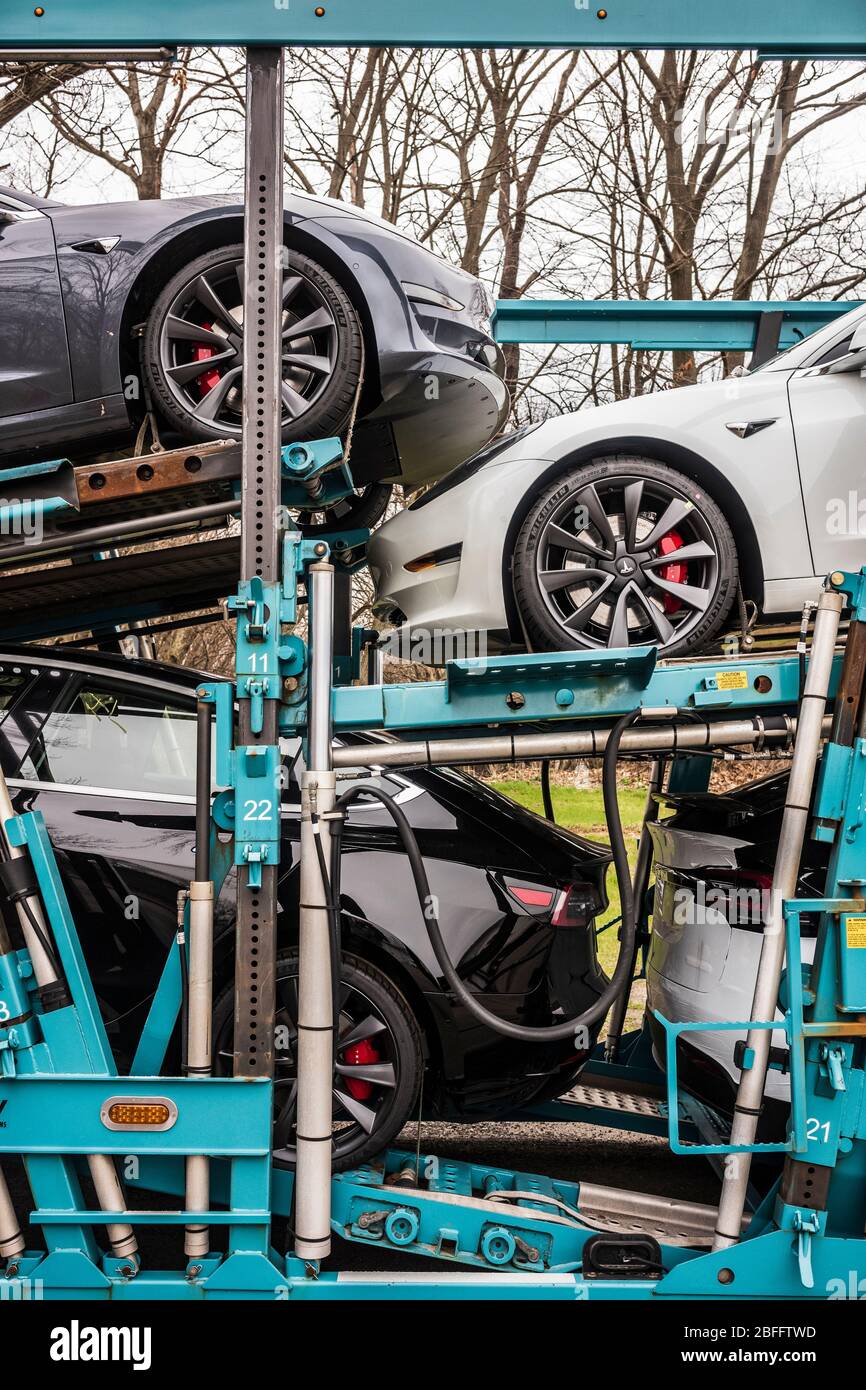 Vestal, NY/USA - 11 aprile 2020: Un semirimorchio che traina sette modelli Tesla 3 e X, verniciato bianco, nero e argento, si siede parcheggiato durante la notte Foto Stock