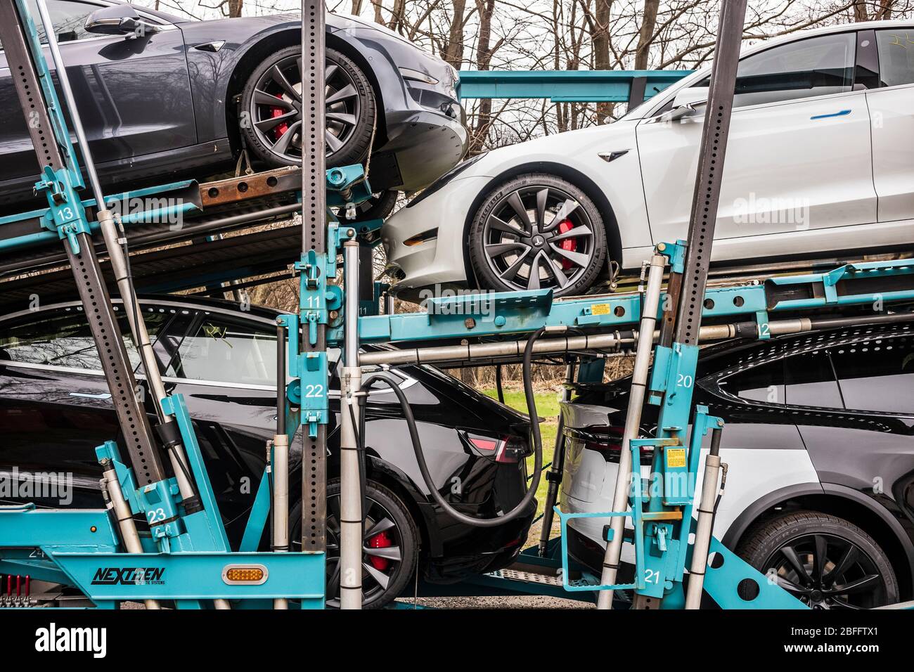 Vestal, NY/USA - 11 aprile 2020: Un semirimorchio che traina sette modelli Tesla 3 e X, verniciato bianco, nero e argento, si siede parcheggiato durante la notte Foto Stock