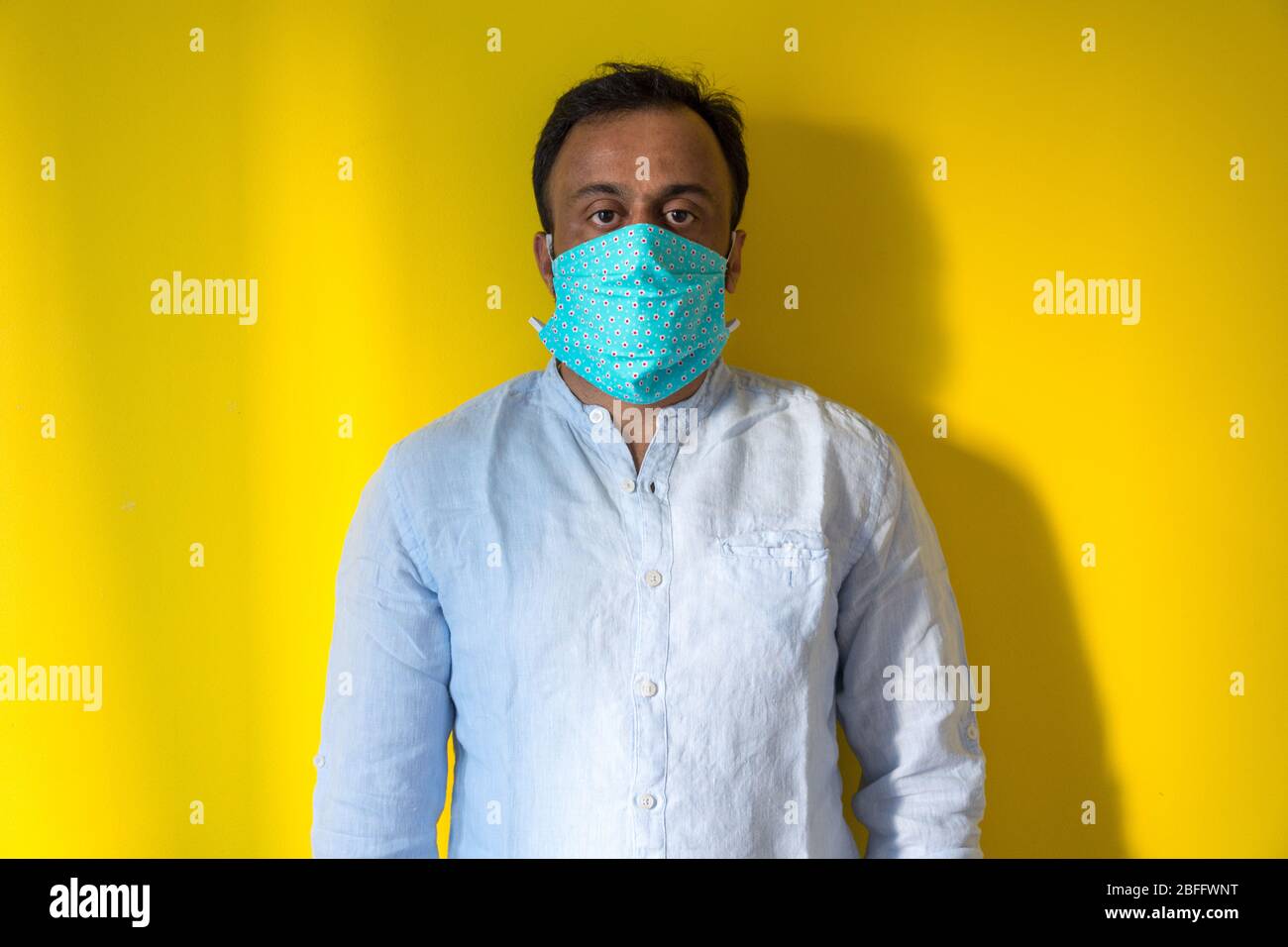 Modello maschio indossato in casa maschera facciale per evitare infezioni da virus corona durante la pandemia corona . Covid19 Foto Stock