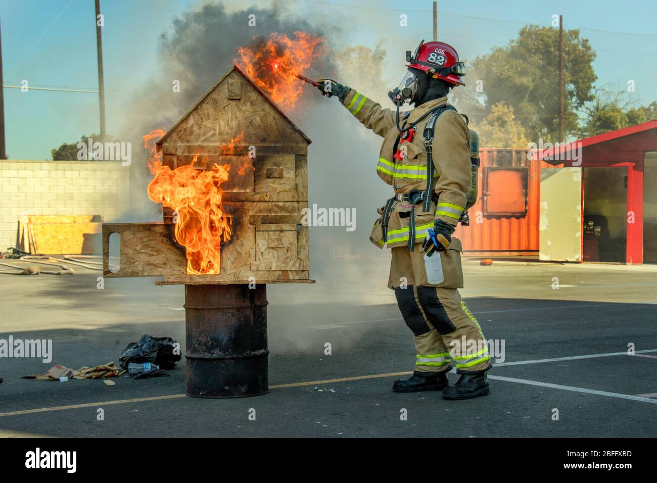 Utilizzando una "casa di tiro" appositamente costruita con sezioni mobili, un vigile del fuoco dimostra i modi in cui il fuoco può diffondersi attraverso una struttura presso una dimostrazione del reparto antincendio a Costa Mesa, CA. Foto Stock