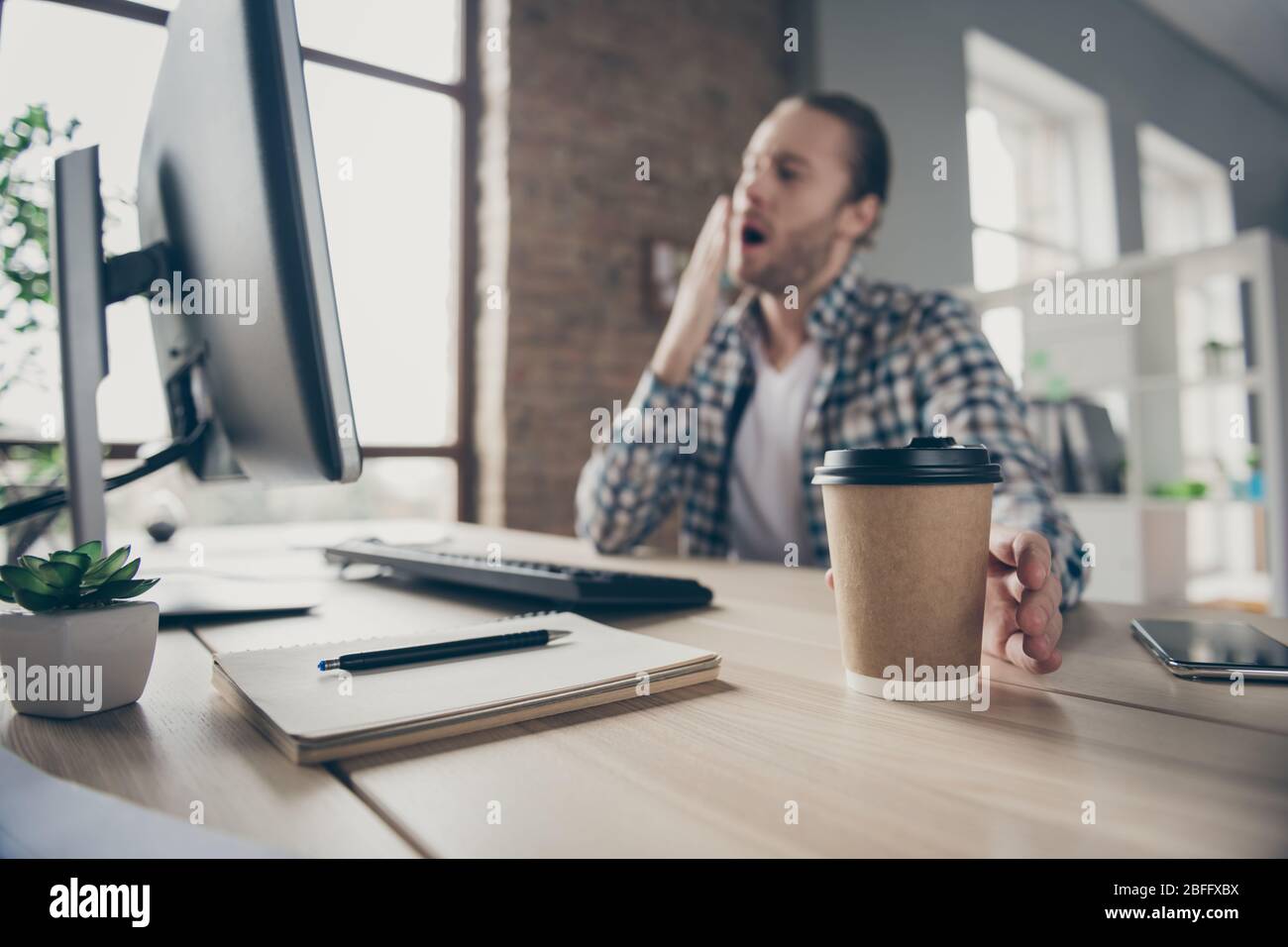 Sfocata foto fuoco di bel business ragazzo guardare monitor computer sul tavolo fine scadenza rapporto in tempo bisogno di un po 'di caffè prendere fresco tazza di imbardata Foto Stock