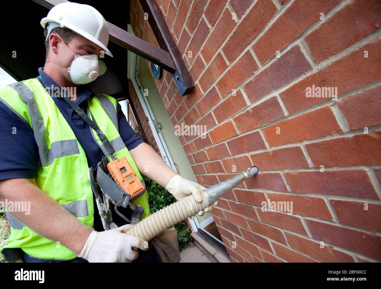 Immagine illustrativa della parete di cavità di isolamento. Un lavoratore di totale isolamento tubi soluzioni Rockwool in una cavità della parete. Foto Stock