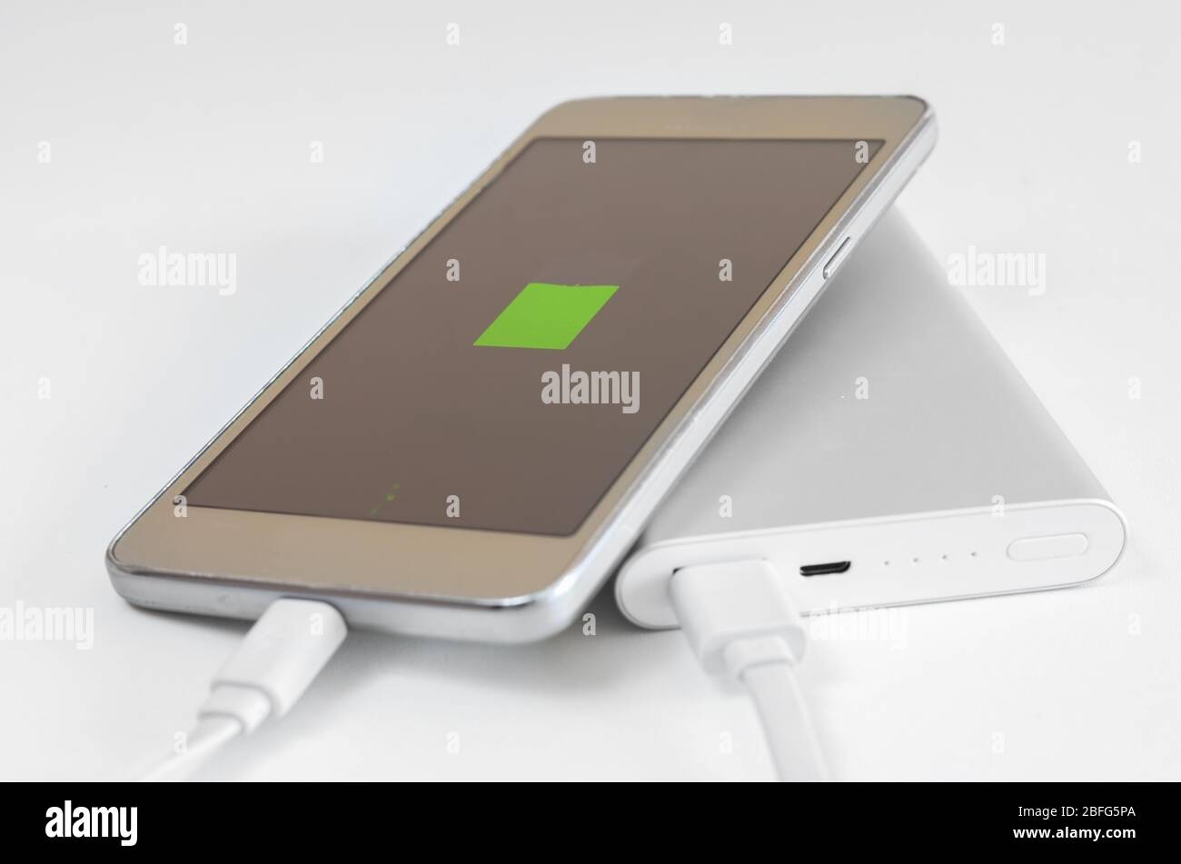 Primo piano della ricarica della batteria dello smartphone scarica dal powerbank su sfondo bianco. Soluto esterno per dispositivi di carica per viaggi . Foto Stock