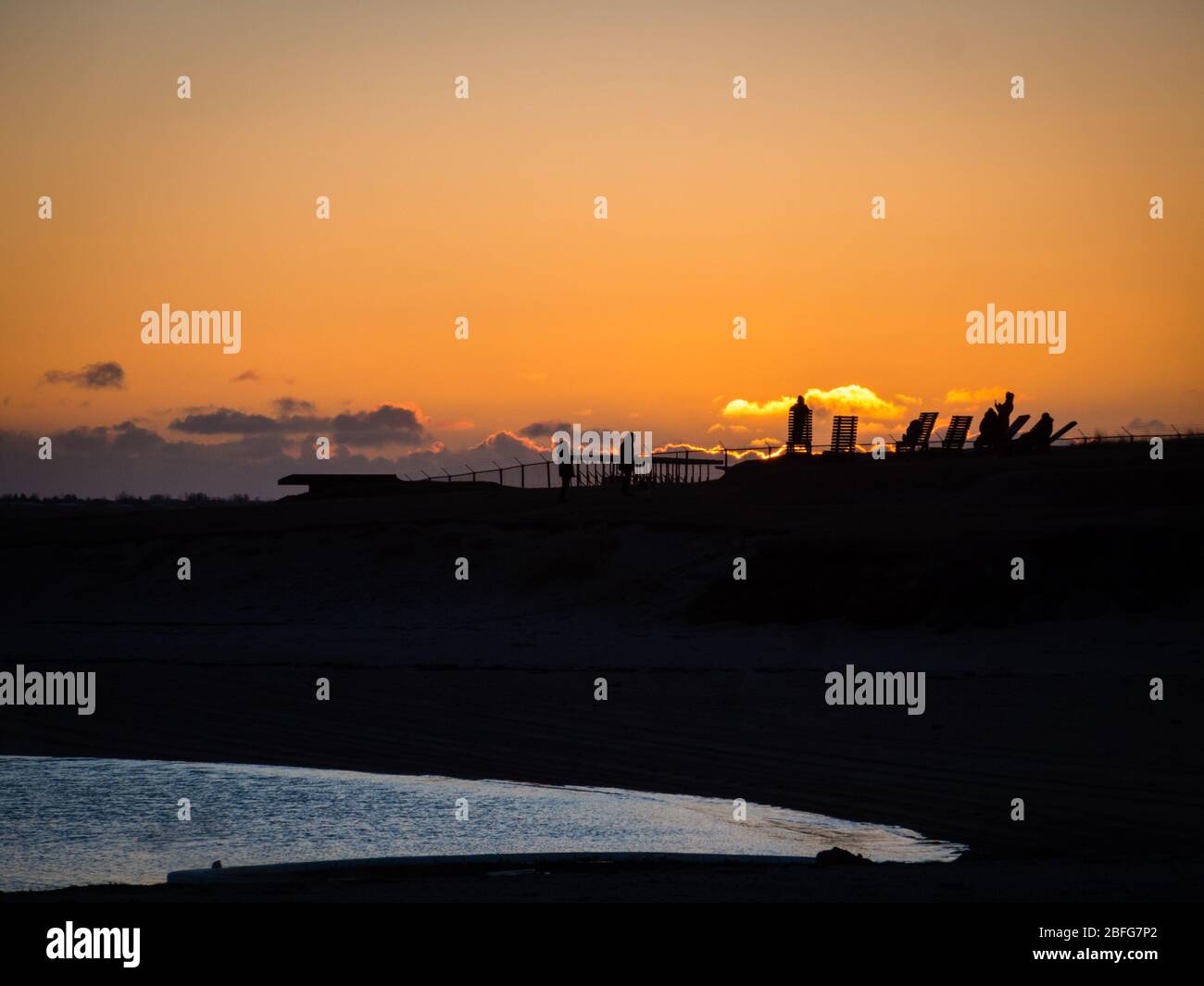 Silhouette di persone che guardano il tramonto spettacolare sulla spiaggia geotermica di Nautholsvik a Reykjavik, Islanda. Serata primaverile, oceano atlantico visibile. CopySpace Foto Stock