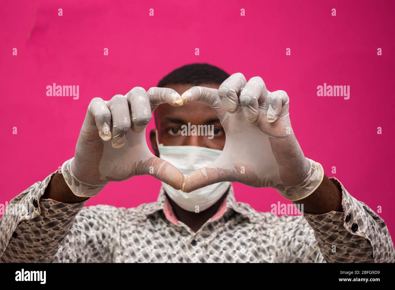 un giovane medico africano isolato su sfondo rosa indossando maschera facciale per prevenire, prevenire, si è impedito dallo scoppio nella società e. Foto Stock