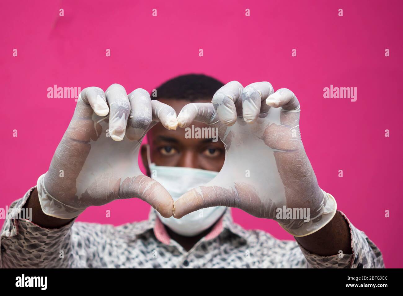 un giovane medico africano isolato su sfondo rosa indossando maschera facciale per prevenire, prevenire, si è impedito dallo scoppio nella società e. Foto Stock