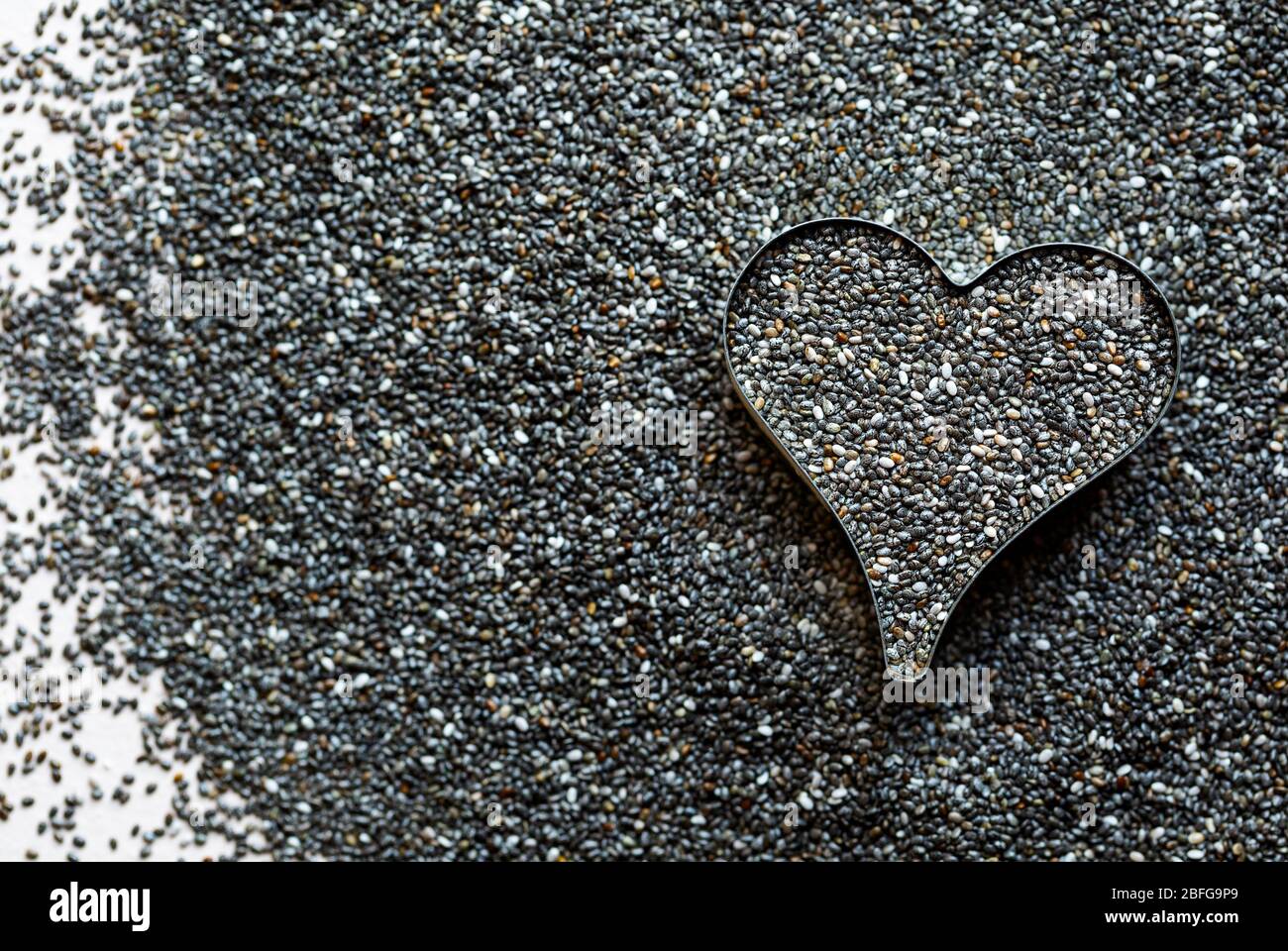 Vista dall'alto del seme di chia organico in un contenitore a forma di cuore Foto Stock