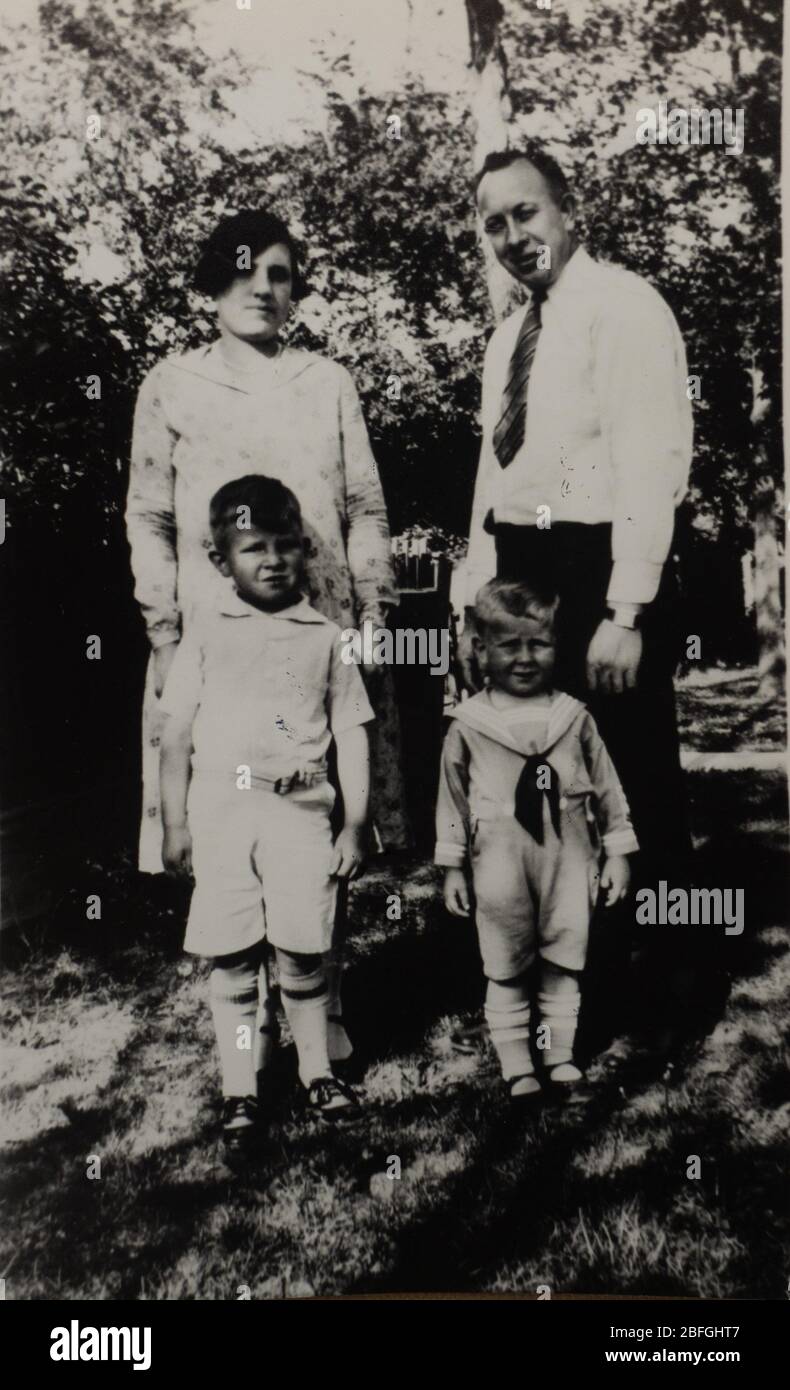 fotografia di famiglia degli anni '30 dei genitori e dei loro due figli. Fotografato all'aperto in bianco e nero. Foto Stock