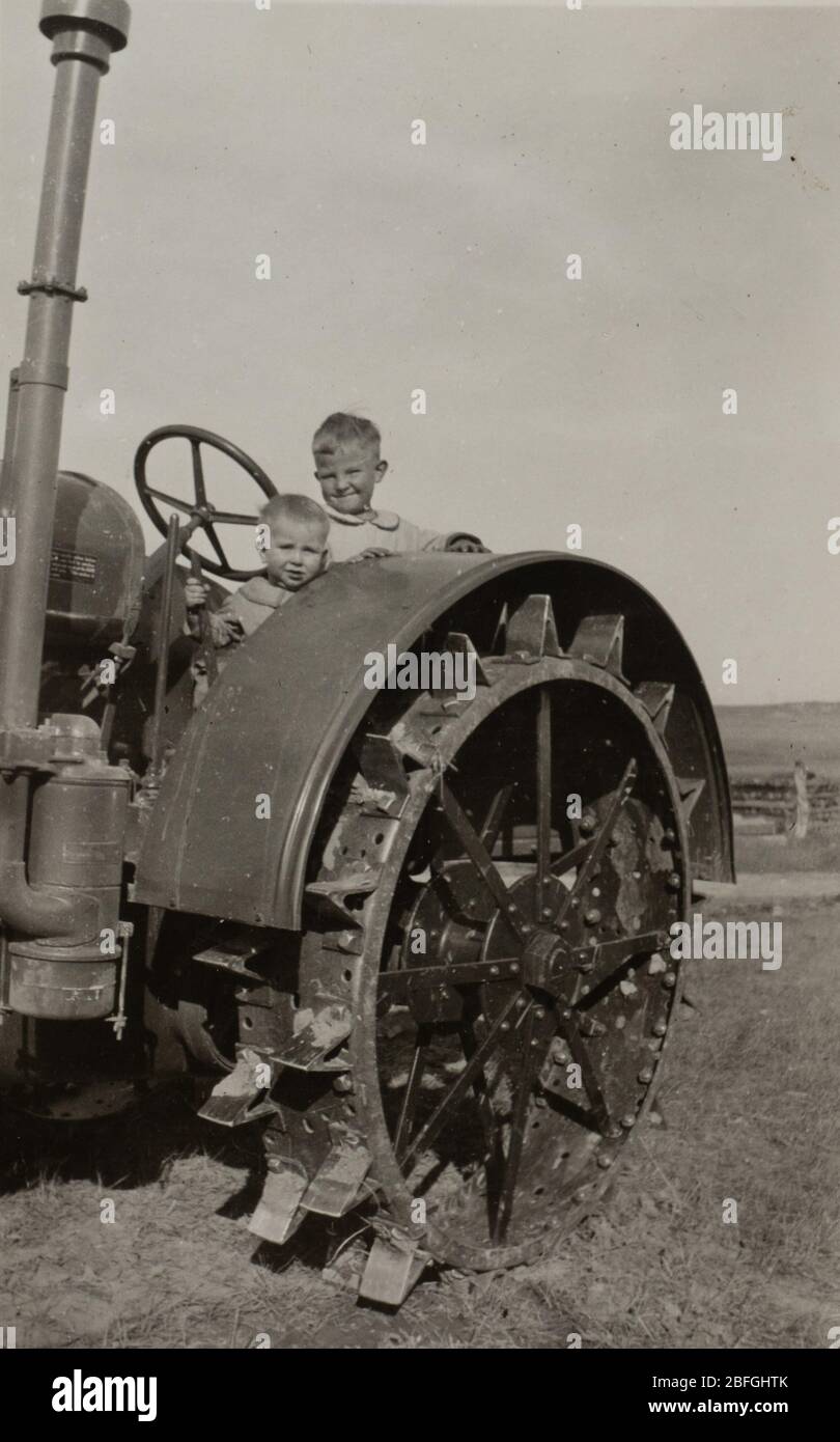 Foto in bianco e nero di due fratelli su un trattore. Fotografato negli anni '30 in Montana. Foto Stock