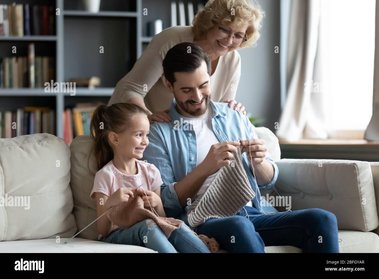 Famiglia multi-generazionale godere di hobby comune maglia seduto sul divano Foto Stock