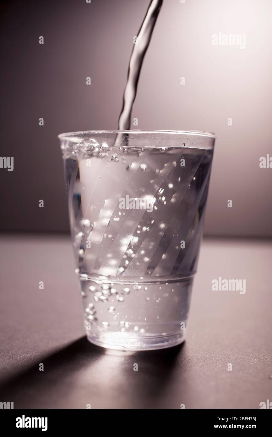 Versare acqua nel bicchiere Foto Stock