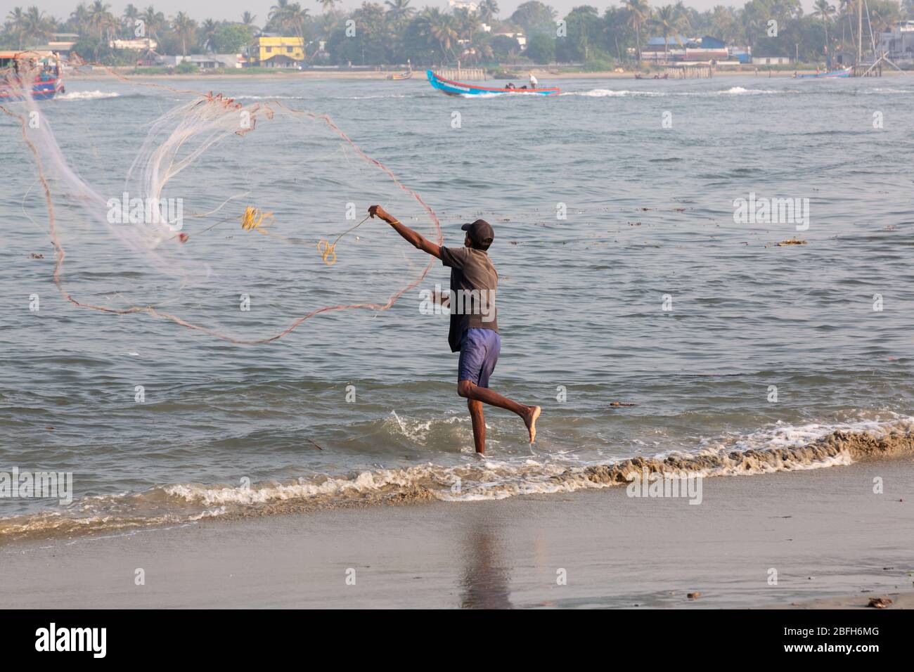 Kochi, Kerala - 30 dicembre 2019: Pescatore che gettò la sua rete dal forte spiaggia kochi, kerala india Foto Stock
