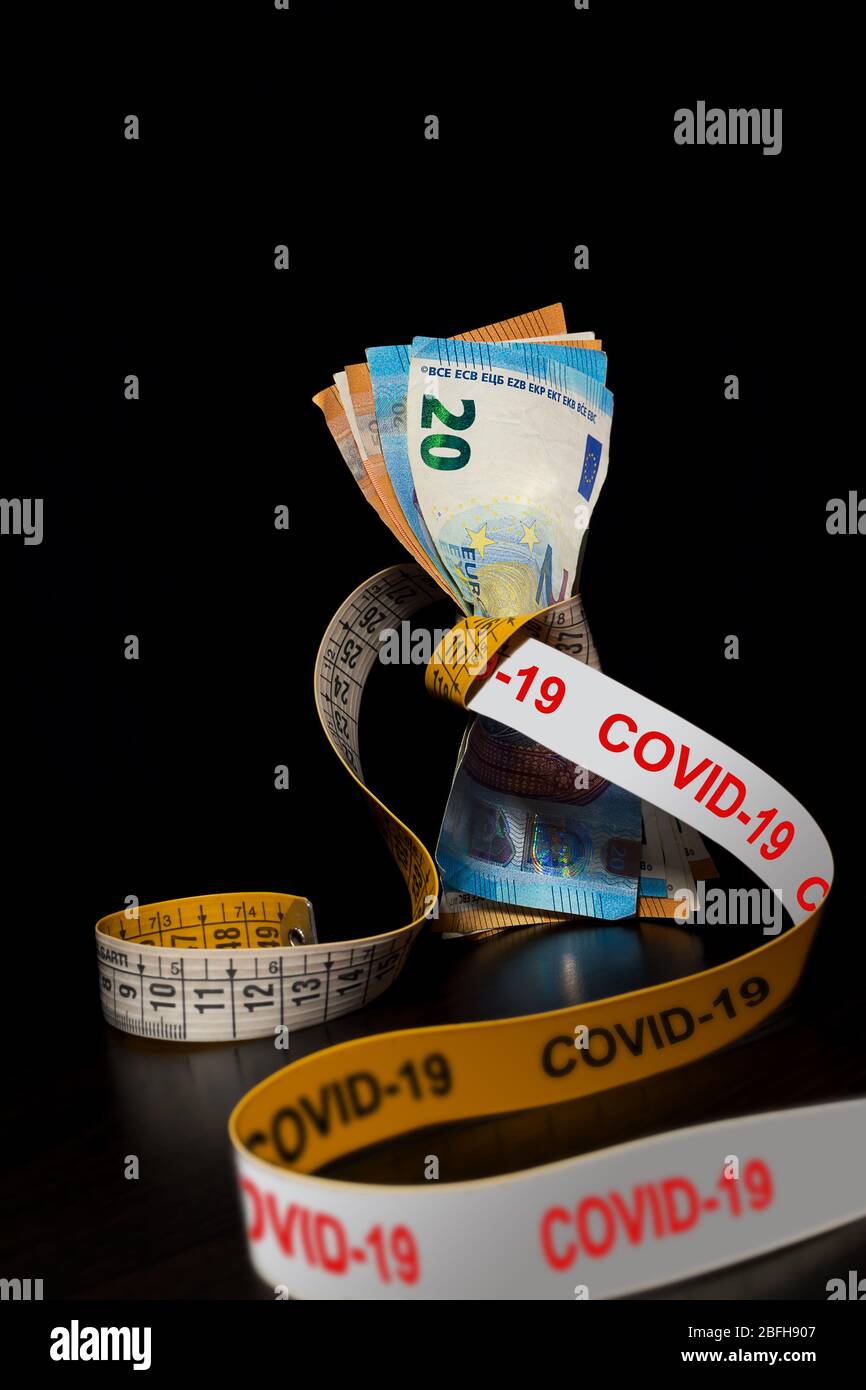Le banconote strette da un nastro con Covid-19 scritto su nero per il concetto di crisi finanziaria causata dalla pandemia di Coronavirus Foto Stock