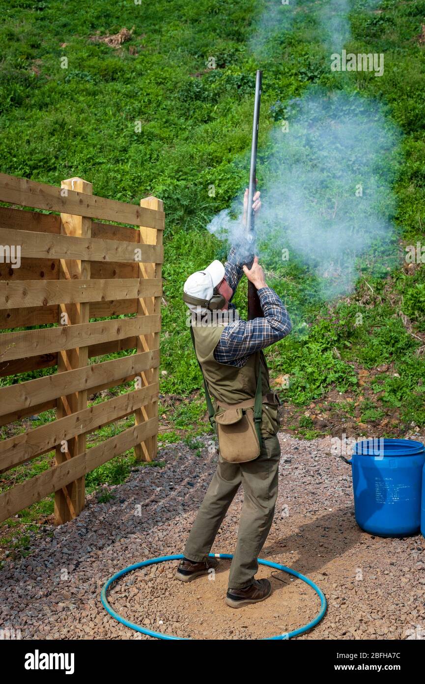 Un'antica pistola di blocco della selce sparata da un uomo durante una competizione di tiro al piccione di argilla (nota: Questo è il numero 4 in una serie di 6 colpi che mostrano il fumo dalla pistola durante il tiro) Foto Stock