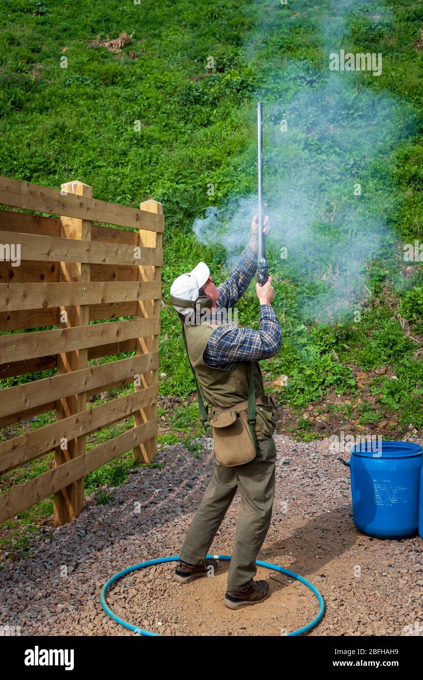 Un'antica pistola di blocco della selce sparata da un uomo durante una competizione di tiro al piccione di argilla (nota: Questo è il numero 6 in una serie di 6 colpi che mostrano il fumo dalla pistola durante il tiro) Foto Stock