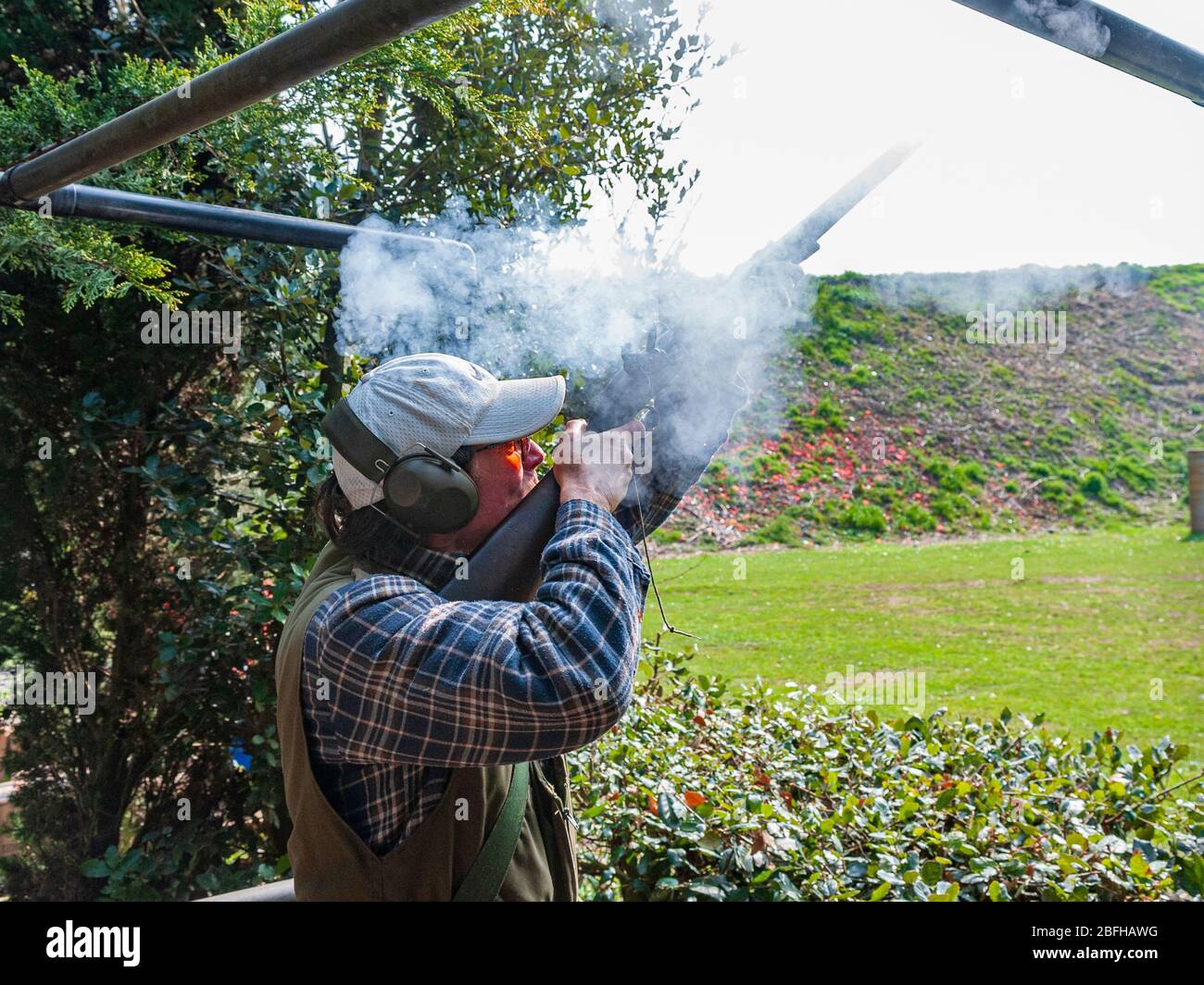 Un'antica pistola di blocco della selce che è sparata da un uomo durante una competizione di tiro del piccione di argilla Foto Stock