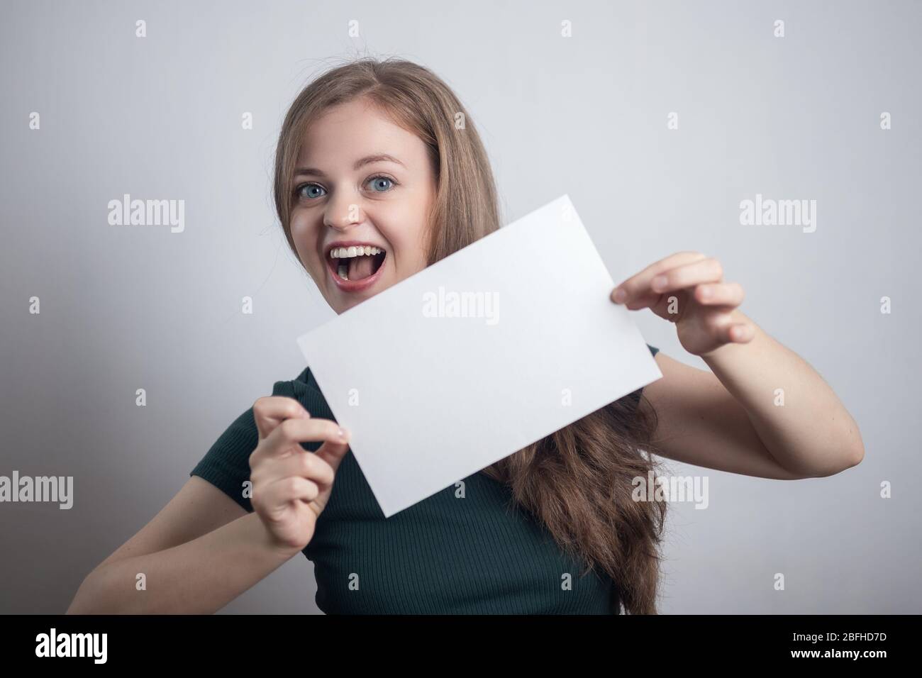 Sorridente giovane donna caucasica ragazza tenendo bianco foglio di carta con spazio per le copie Foto Stock