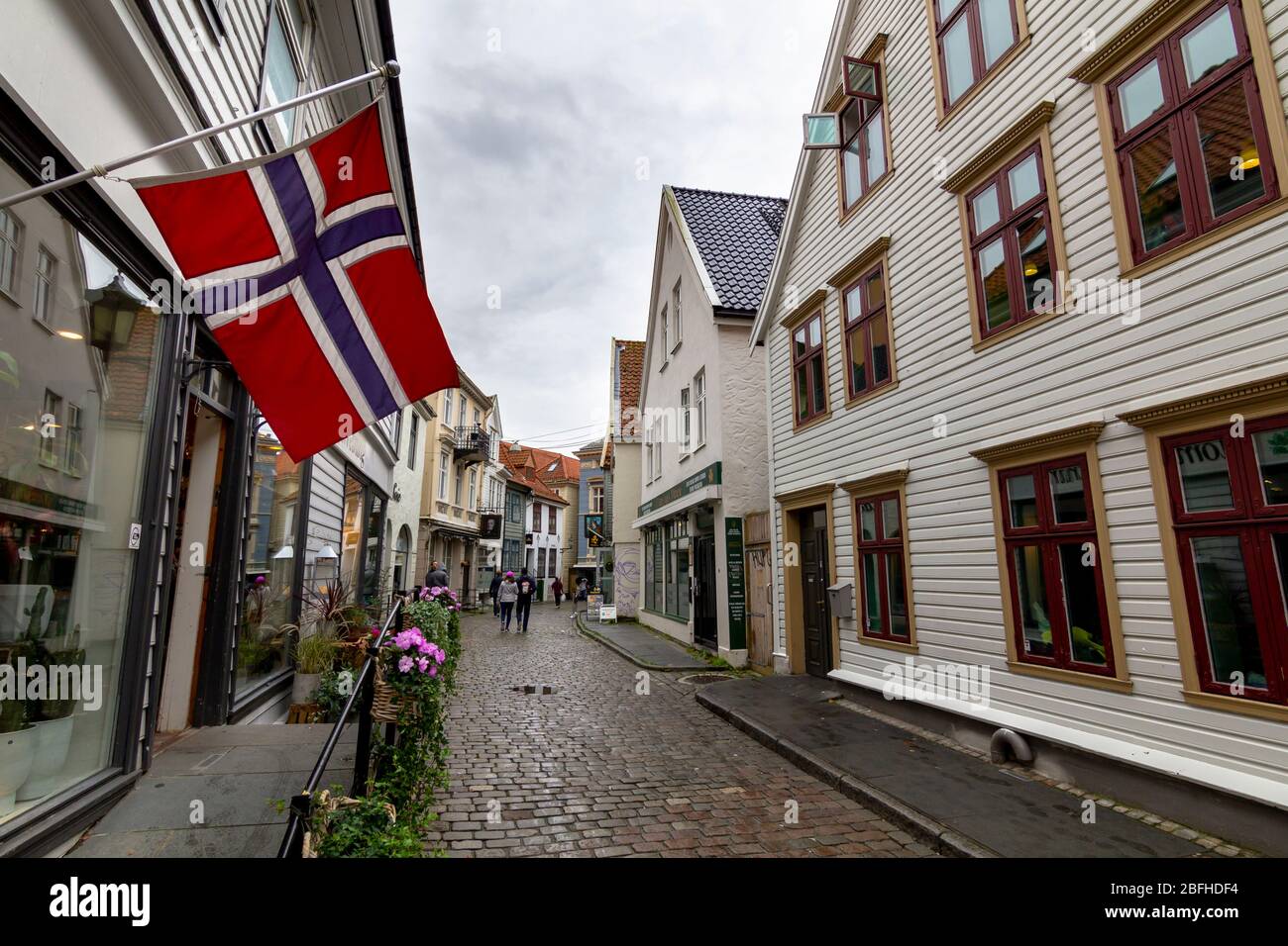 Bergen, Norvegia - 13 agosto 2019: Vista della strada con bandiera norvegese appesa in una tipica casa in legno nella città di Bergen Foto Stock