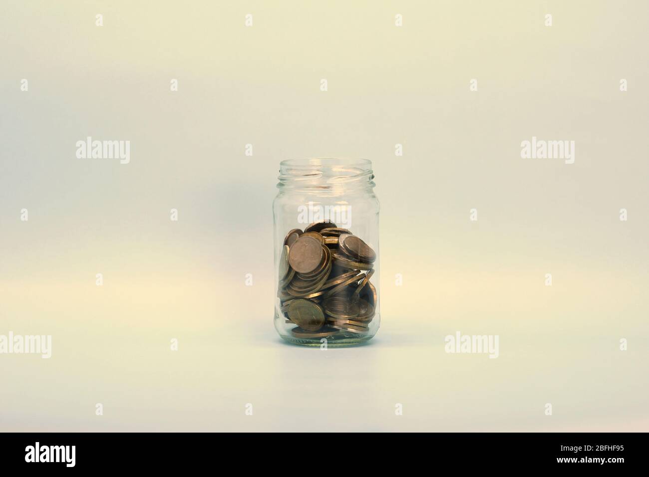 Monete metalliche, rubli russi, giacciono in un vaso di vetro trasparente su uno sfondo chiaro. Posizionare per testo e disegno. Foto Stock