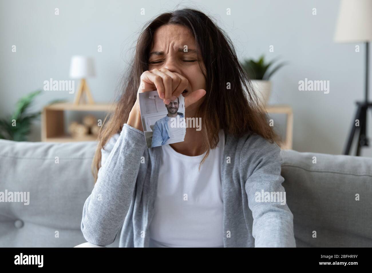 Donna depressa che piange, tiene il ragazzo o immagine del marito Foto Stock