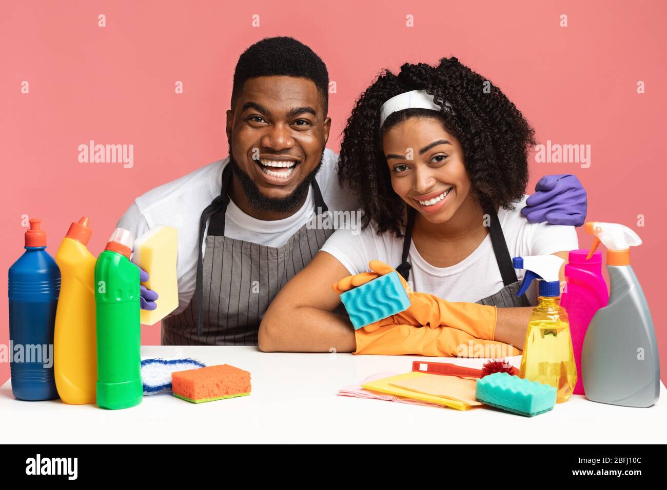 Pulizia della molla. Coppia nera seduta al tavolo con molti detergenti Foto Stock