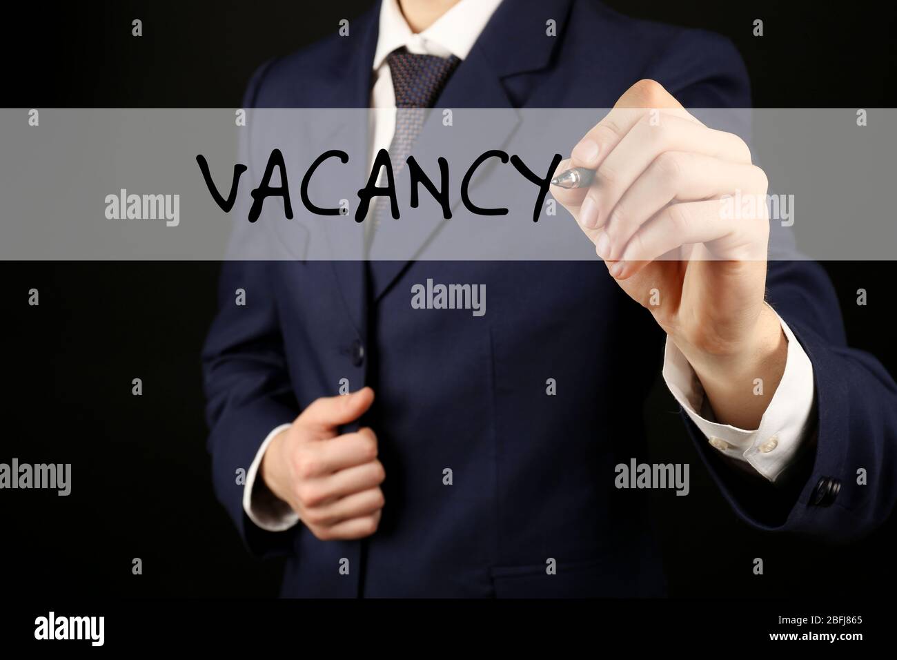 Uomo d'affari che scrive VACANCY alla lavagna trasparente, primo piano Foto Stock