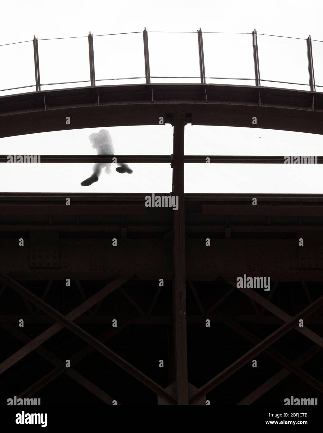 Silhouette di una persona che cammina sulla piattaforma trasparente al primo piano della Eiffel come visto dal basso, Parigi Foto Stock