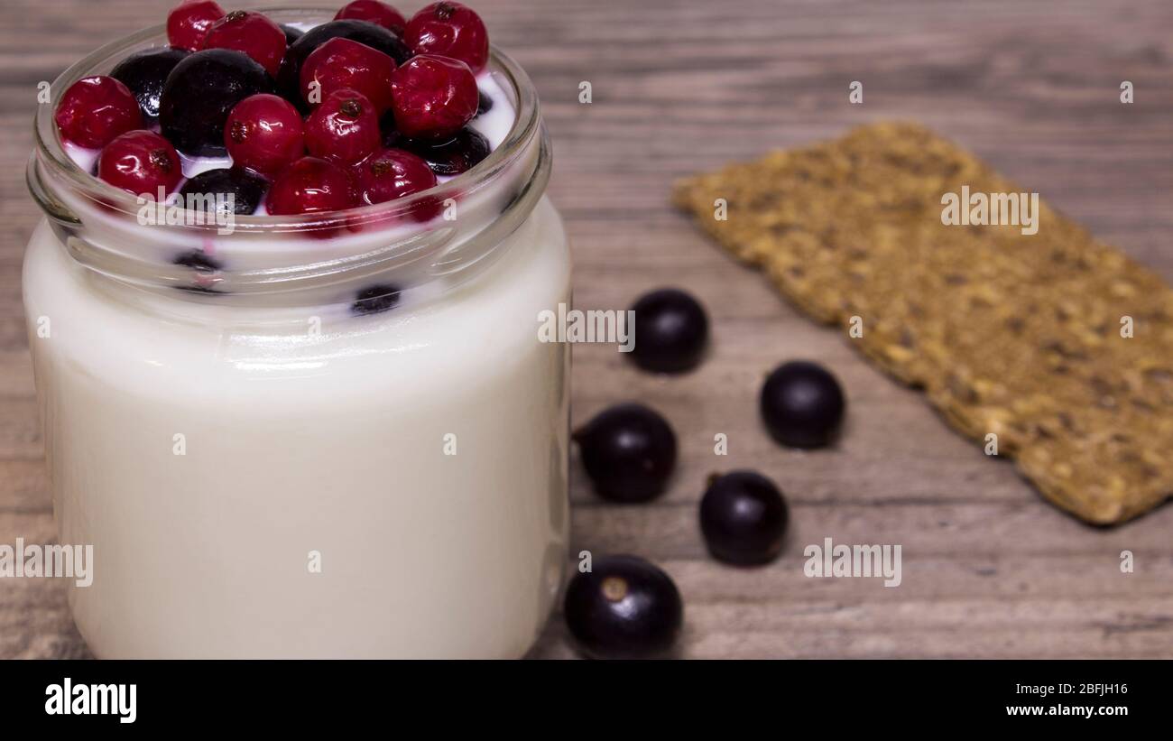 Yogurt greco, latte, frullati, mirtilli e ribes in un vaso di vetro su un tavolo di legno, detox, dieta Foto Stock