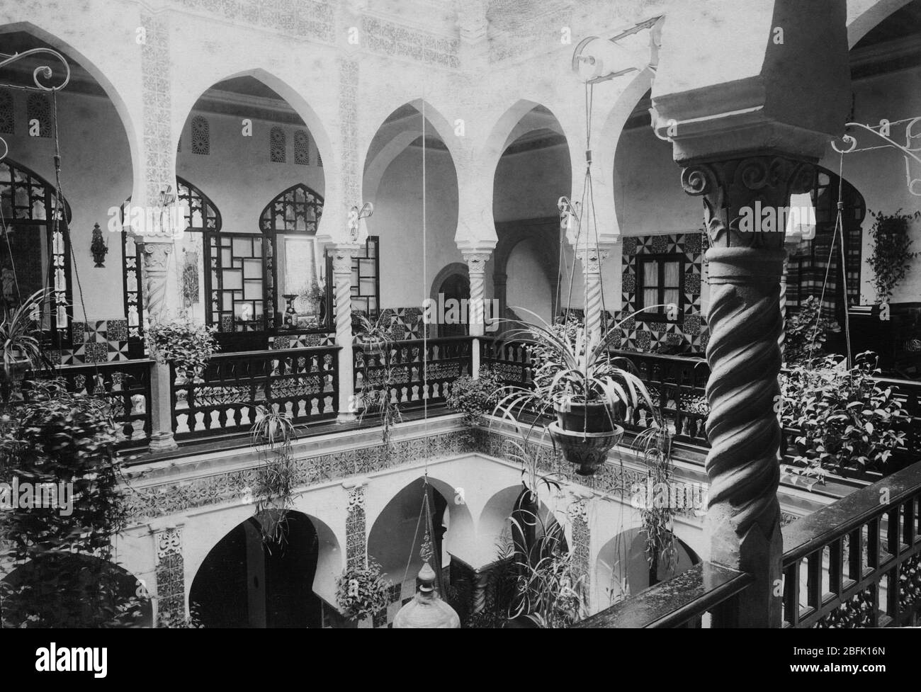 Una bella casa a Riyadh ad Algeri, Algeria francese, Africa. Questa vista è da un balcone sul cortile interno, che è un giardino pensile virtuale. Ci sono file di libri all'interno della porta più buia che attraversa il balcone. Gli anni '1880 o '1890 Per vedere le mie immagini vintage correlate ad altri luoghi, Search: Prestor vintage places African Foto Stock