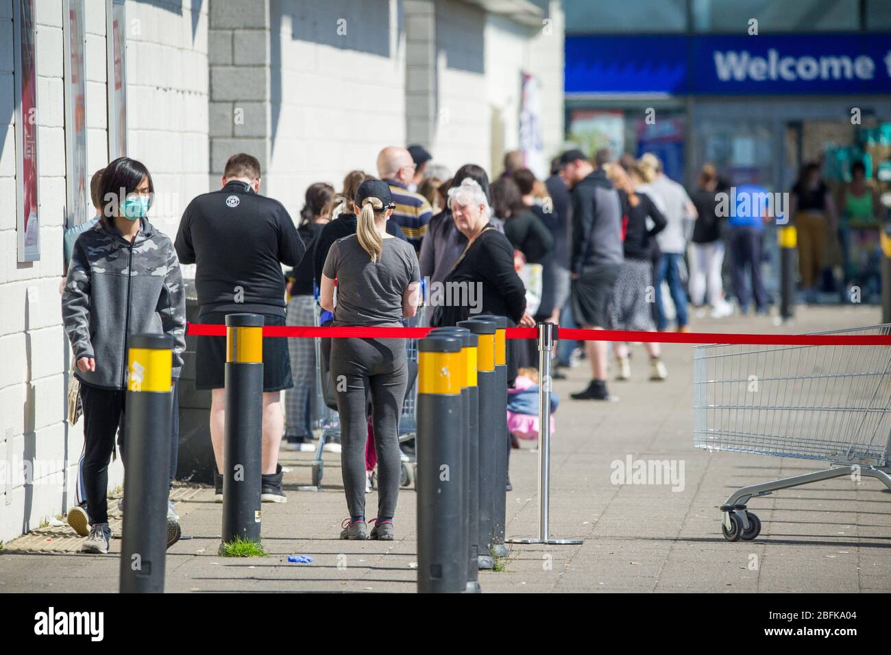 Glasgow, Regno Unito. 19 Apr 2020. Nella foto: Lunghe file di persone aspettano in coda fuori dai negozi B&M durante un weekend caldo e soleggiato sotto il blocco Coronavirus (COVID-19). Le distanze sociali possono essere viste come la coda della gente. Ad oggi nel Regno Unito i casi confermati di persone infette sono 120,067 con 16,060 morti. Credit: Colin Fisher/Alamy Live News Foto Stock