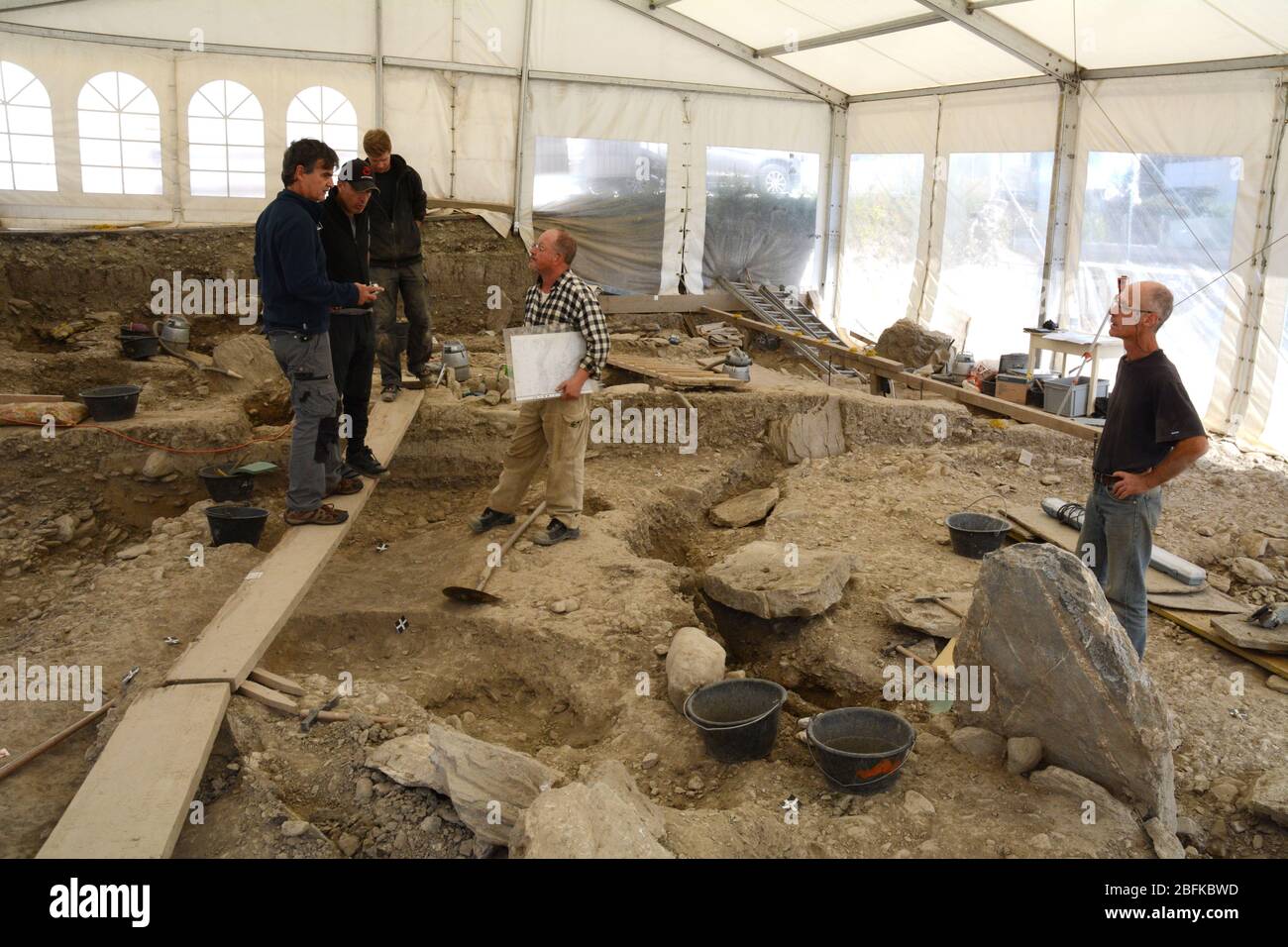Un team archeologico che scava scheletri sotto una tenda in un sito di sepoltura neolitico nella città di Sion nella Valle del Rodano in Svizzera. Foto Stock