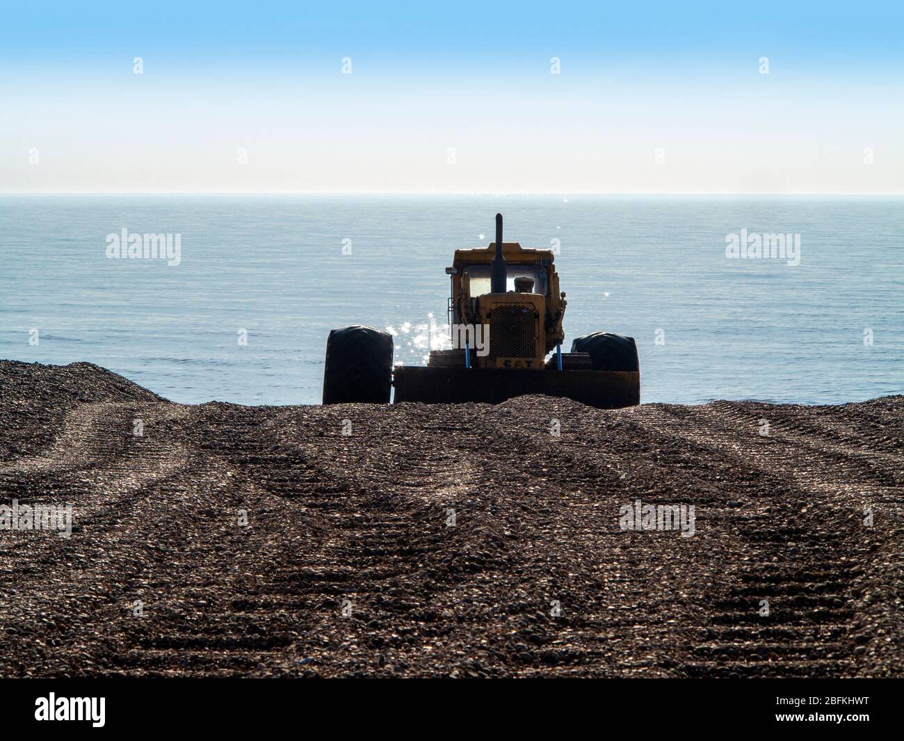 Bulldozer utilizzato come lanciatore di barche da pesca parcheggiato sulla spiaggia di ghiaia con mare spiaggiante dietro e tracce di segni che conducono ad esso. Aldeburgh Suffolk Foto Stock