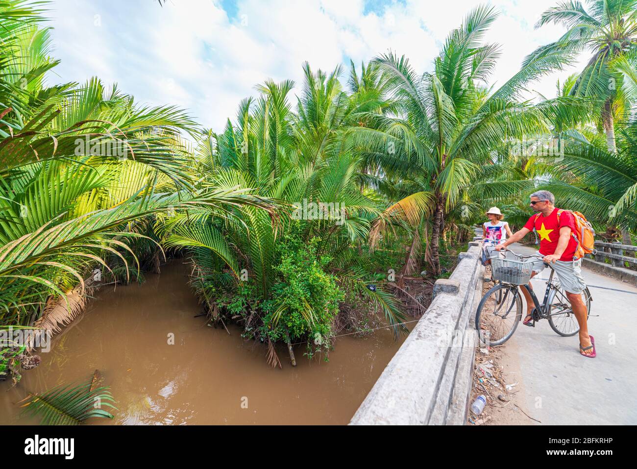 Coppia turistico equitazione bicicletta nella regione del Delta del Mekong, Ben tre, Vietnam del Sud. Donna e uomo avendo divertimento escursioni in bicicletta sul sentiero tra il verde woodl tropicale Foto Stock