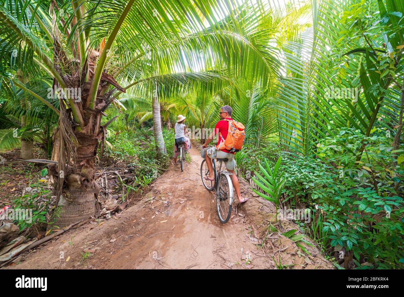 Coppia turistico equitazione bicicletta nella regione del Delta del Mekong, Ben tre, Vietnam del Sud. Donna e uomo avendo divertimento escursioni in bicicletta sul sentiero tra il verde woodl tropicale Foto Stock