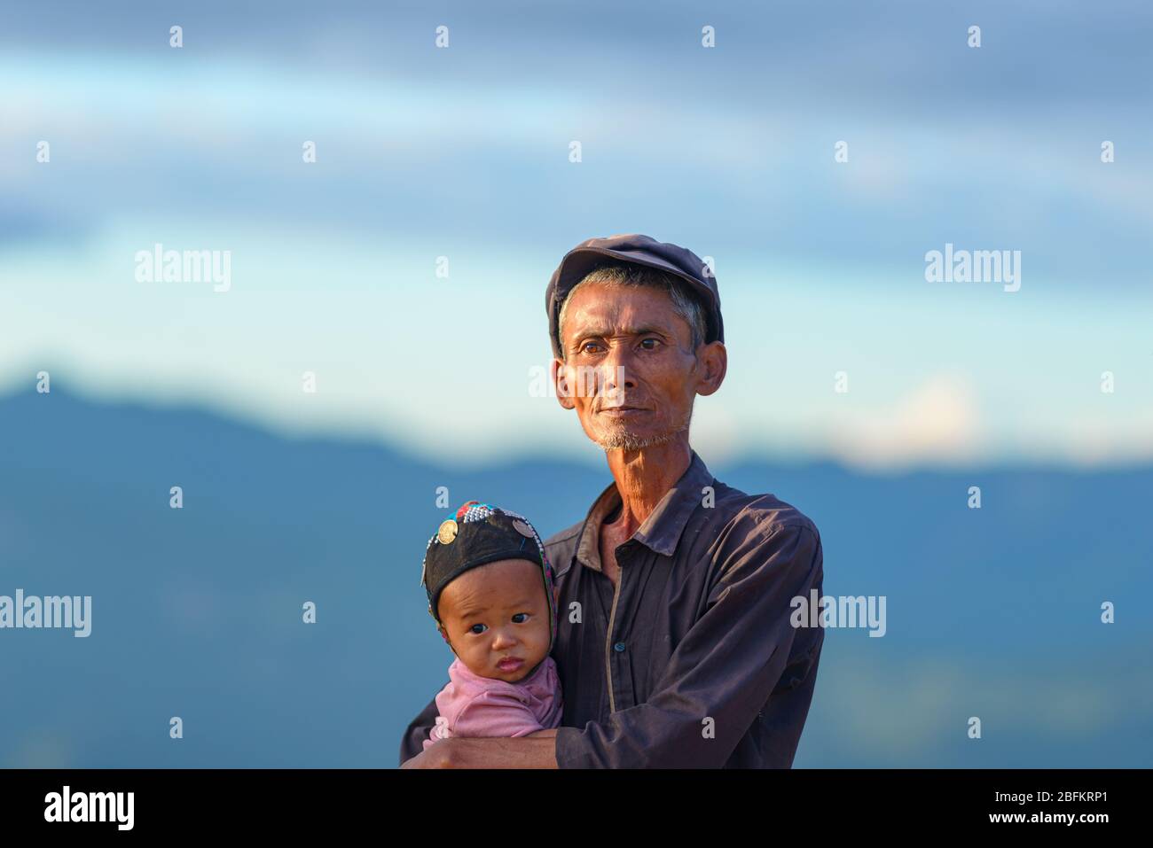 Phongsaly, Laos - 2 novembre 2019: Ritratto uomo anziano Akha tenendo bambino indossando cappello tradizionale appartenente a gruppo etnico minoritario che vive in collina Foto Stock