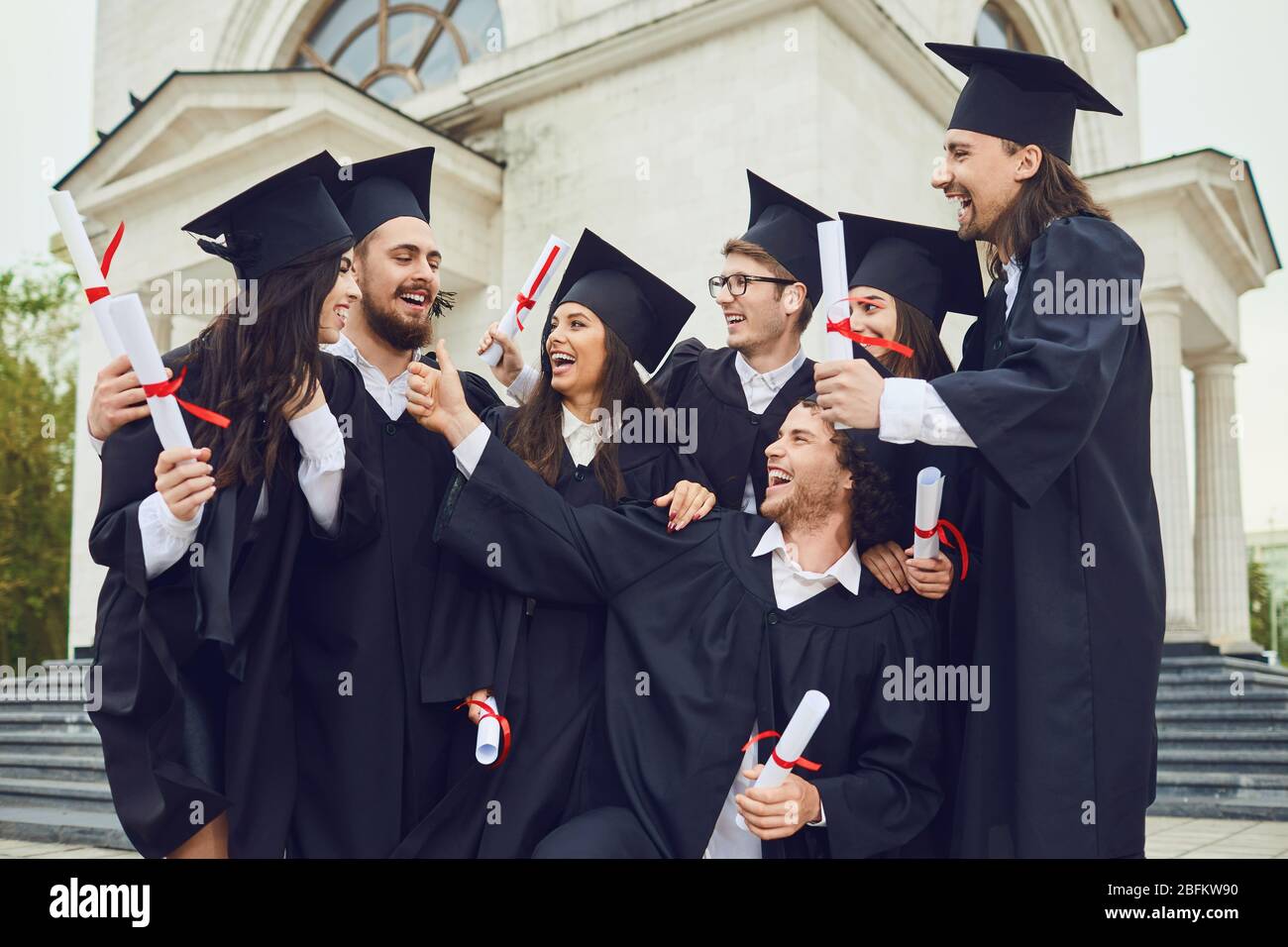 Un gruppo di laureati con scroll nelle loro mani sorridono Foto Stock