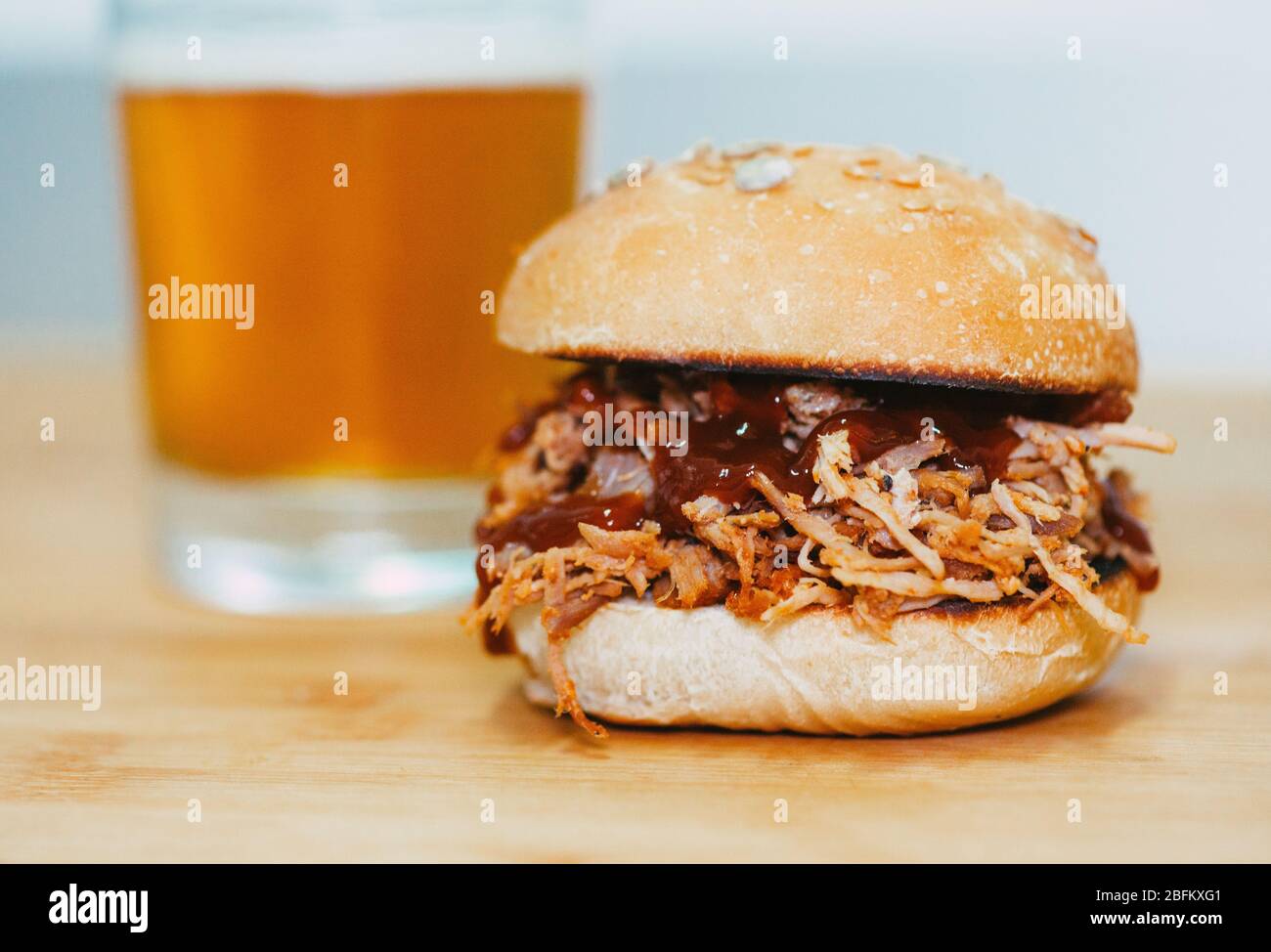 Hamburger barbecue di maiale caldo con mani e birra fresca su un set di legno Foto Stock