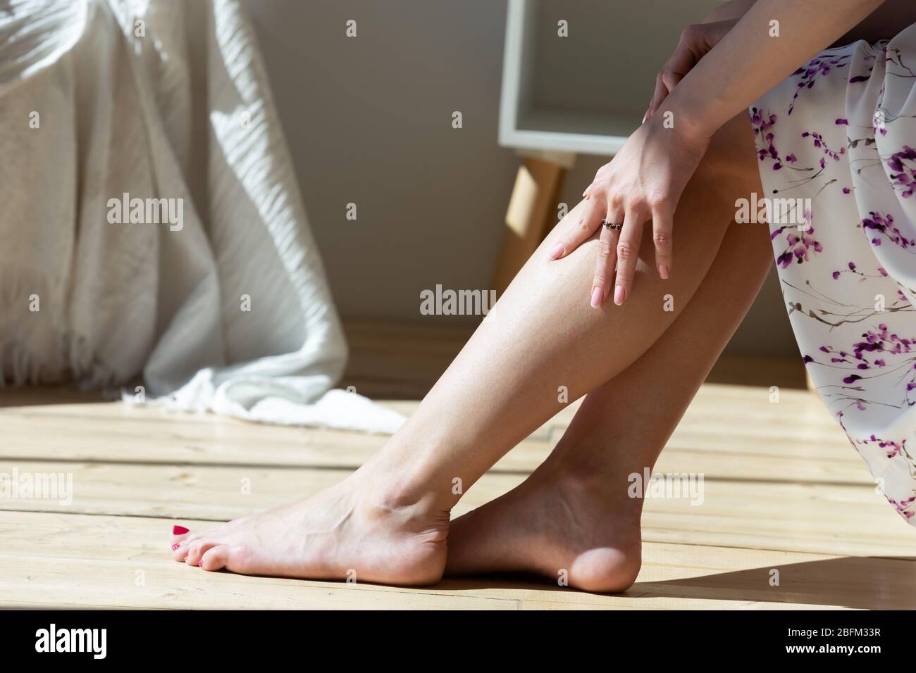 Primo piano infelice giovane donna che soffre di dolore alle gambe. Foto Stock