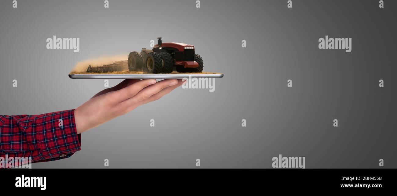 L'agricoltore che detiene un tablet autonoma con il trattore. La realtà aumentata e la trasformazione digitale in agricoltura. Smart concetto di agricoltura Foto Stock