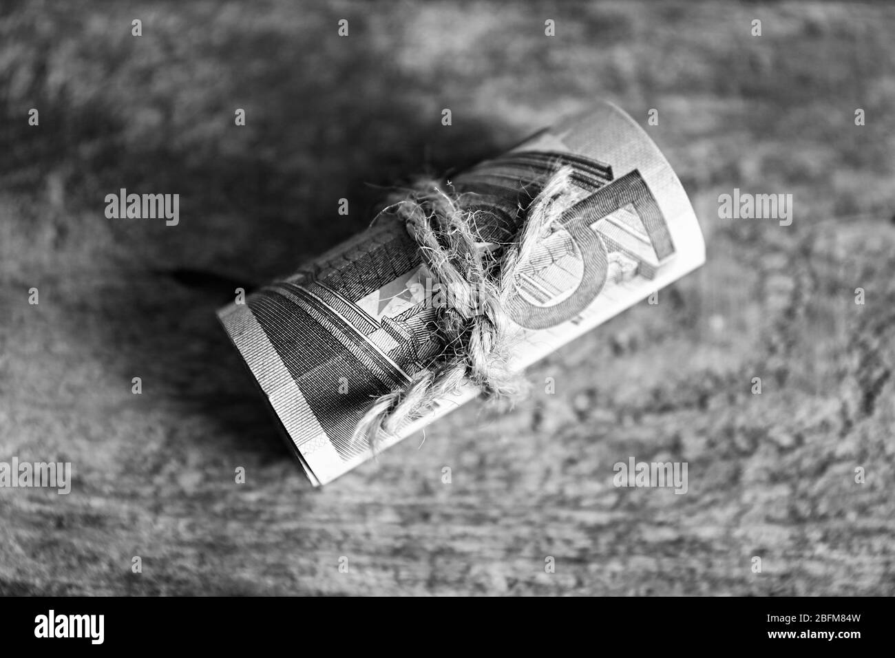 Rotolo di banconote in euro su sfondo di legno Foto Stock