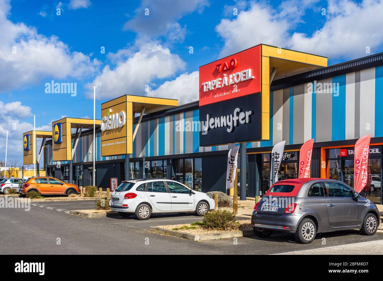 Fila di negozi su un'area commerciale che mostra la segnaletica aziendale sopra gli ingressi dei negozi - Chatellerault, Vienne, Francia. Foto Stock