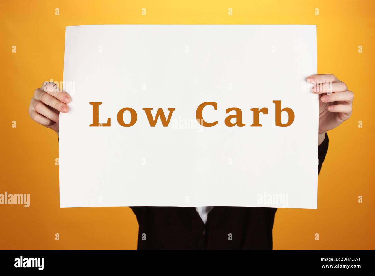 Donna che tiene carta con basso-Carb testo su sfondo a colori Foto Stock