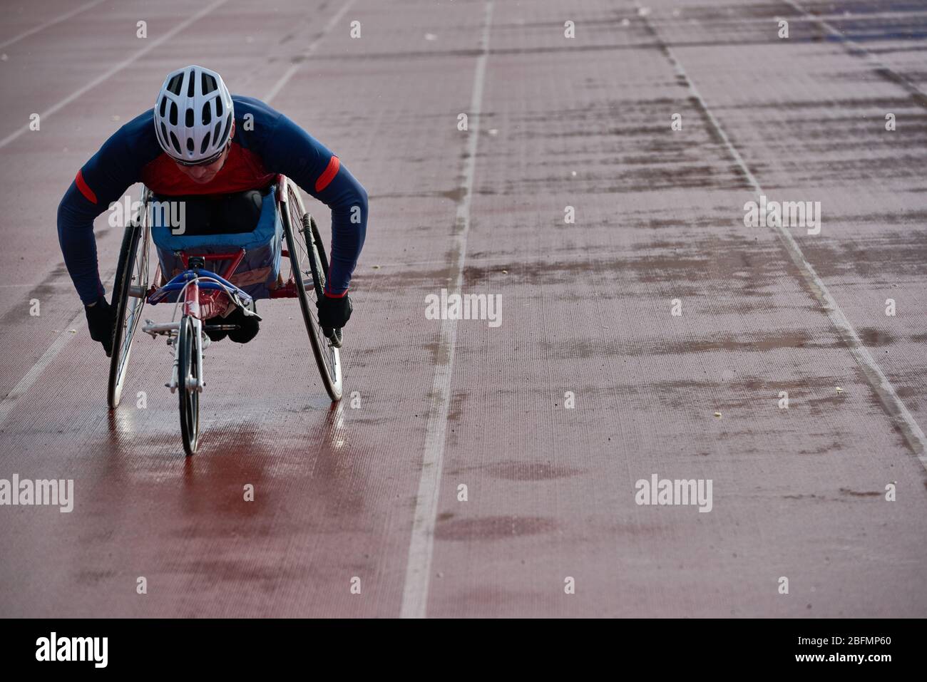 Preparazione per la maratona su sedia a rotelle. Paraplegico atleta maschile in carrozzina da corsa riscaldamento da solo presso pista all'aperto e stadio da campo Foto Stock