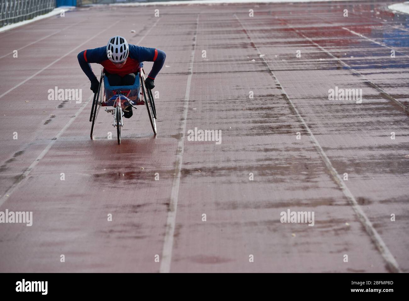 Atletica su sedia a rotelle. Atleta disabile in sedia da corsa per prepararsi a una gara importante mentre si allena da solo in pista all'aperto Foto Stock