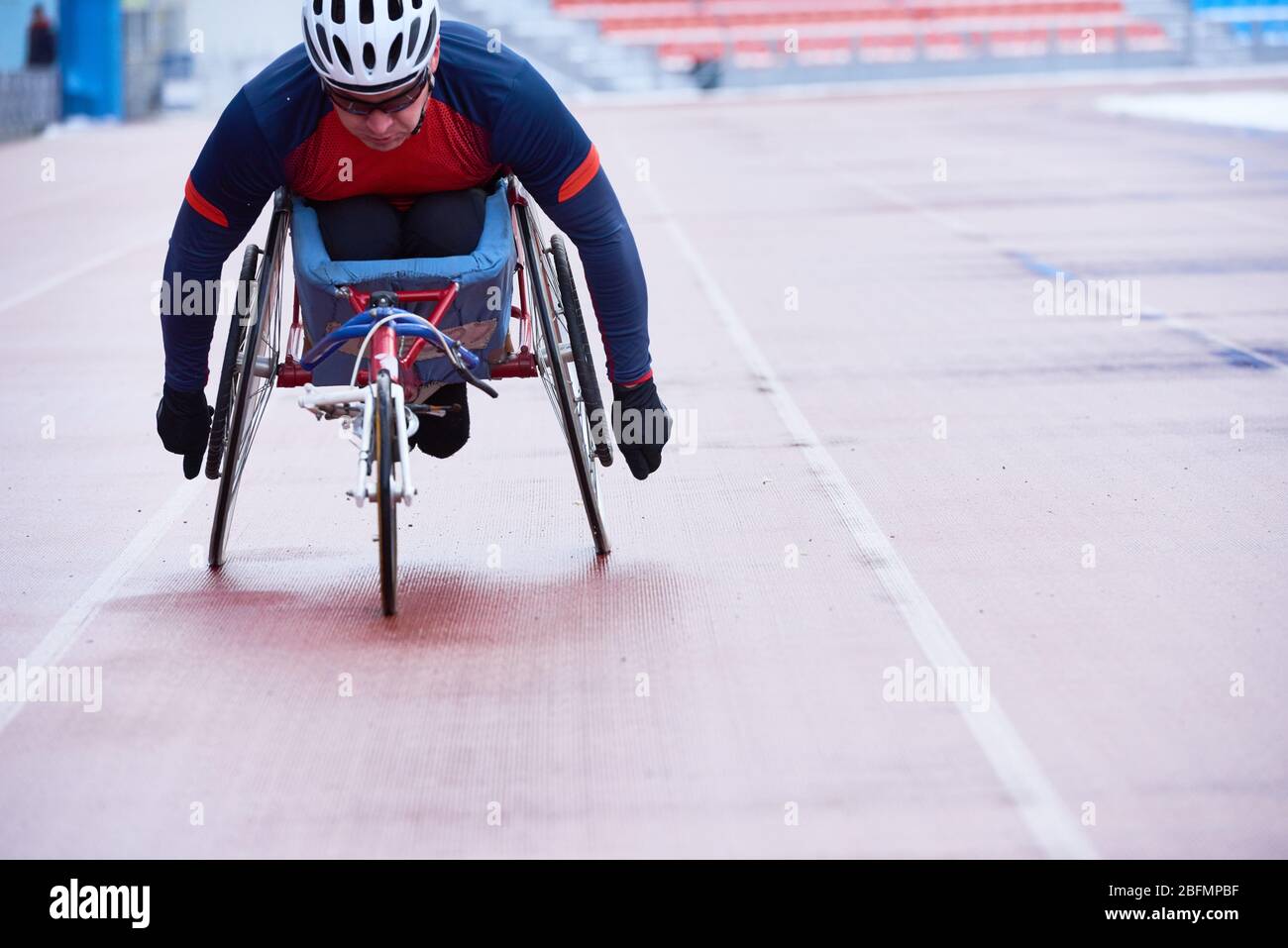 Atletica su sedia a rotelle. Determinato atleta paraplegico maschile in abbigliamento sportivo e casco che partecipa a gara di carrozzina in pista all'aperto e. Foto Stock
