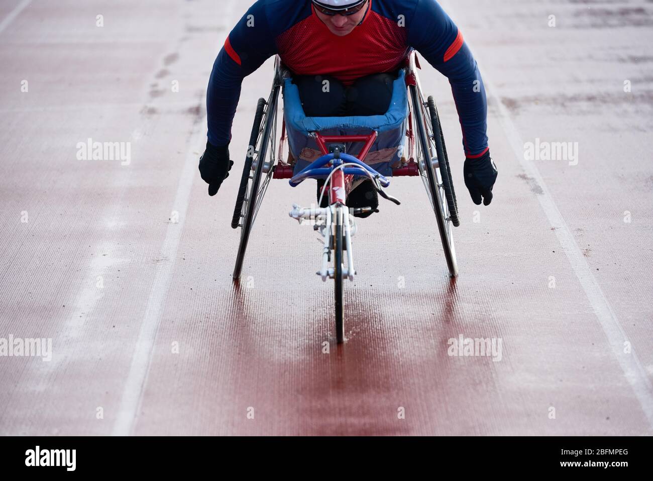 Esecuzione di un'impresa in sedia a rotelle. Vista ravvicinata dello sportivo disabili in sedia da corsa che si riscalda da solo sulla pista all'aperto prima della gara Foto Stock