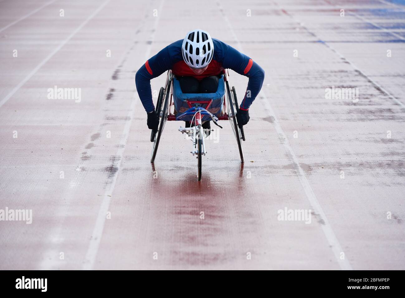 Creazione di record in sedia a rotelle. Atleta maschile fisicamente non in linea con il traguardo mentre gareggiare in carrozzina sportiva su pista all'aperto Foto Stock